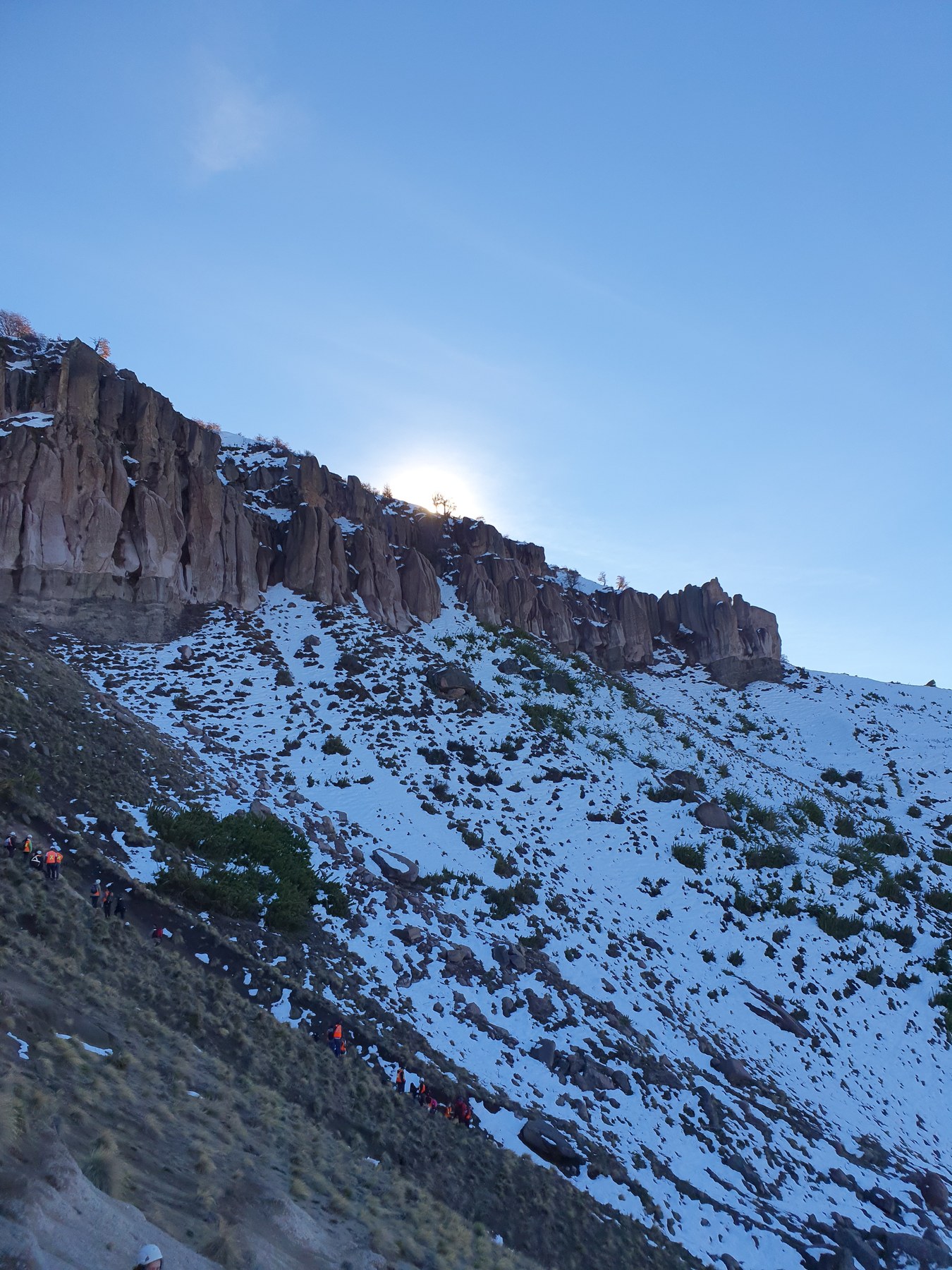Acantilado rocoso nevado con pendiente inestable y equipo de terreno